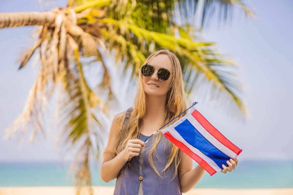 Woman having fun at the beach holding Thailand flag